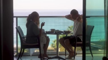 Üç kişilik genç bir aile deniz manzaralı balkonda kahvaltı yapıyor. Mükemmel Günaydın. Otelde. Alanya Türkiye 2021 Yüksek kaliteli 4K görüntü
