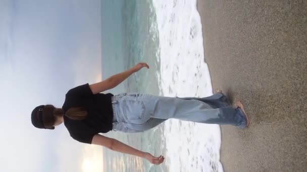 垂直录像 故事卷 一个穿着浅色牛仔裤的年轻女子径直走在海滩上 积极的情绪 自由的生活方式Steadicam 一个人优质Fullhd画面120Fps — 图库视频影像