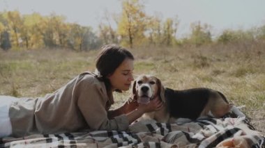 Bir kız çimenli bir çimenlikte uzanır, av köpeğine sarılır ve onu nazikçe öper. Sonbahar Konsepti: Köpek insanın en iyi dostudur, hayvanları sever. Kyiv. Ukrayna 2019