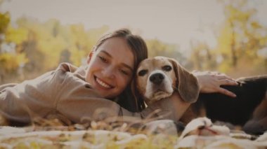 Kapatın. Bir kız çimenli bir çimenlikte, av köpeğine sarılıyor. En iyi arkadaşlar konsepti: köpek insanın en iyi dostudur, hayvanları sever. Kyiv. Ukrayna. 4k
