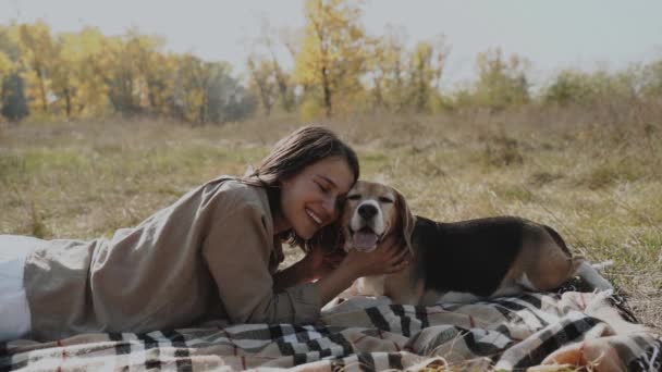 女孩躺在草地上 抱着她的小猎犬 狗是人类最好的朋友 对动物的爱 慢动作120秋日 — 图库视频影像