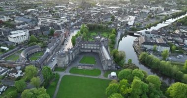 Arial. Kilkenny Kalesi 'ne doğru bir uçuş, yeşil bir parkın içinden. River Nor ve antik Kilkenny kasabası. 5k biçiminde yüksek kaliteli çekimler