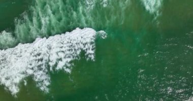 Kristal berrak deniz ve kumsal manzaralı 5k video görüntüleri. Döngülü su yüzeyi dokusu manzarası. Hava manzaralı okyanus dalgaları. Deniz kenarında kum. Portekiz 2023.