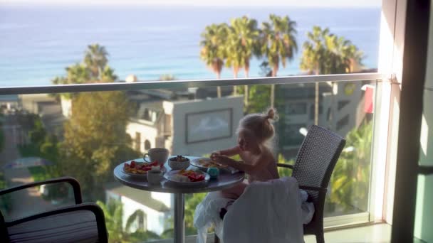 靠近点一个可爱的小女孩在一个露天宾馆的阳台上吃早餐 可以看到迷人的海景 完美的早晨Alanya Turkey 2021高质量4K镜头 — 图库视频影像