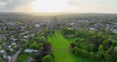 Havadan. İrlanda 'nın yeşil parkından Kilkenny Kalesi' ne doğru bir uçuş. Nor Nehri ve antik kasaba günbatımının arka planına karşı. 5k biçiminde yüksek kaliteli çekimler