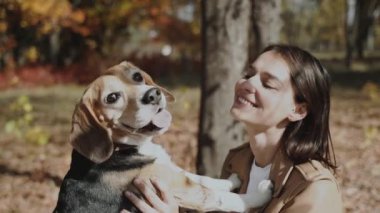 Yakın plan. Kız av köpeğini kucaklıyor ve gülümsüyor. Köpek, insanın en iyi dostudur, hayvanları sever. Yavaş çekim 120