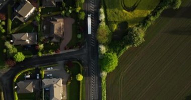 Havadan. Kamera beyaz bir kargo kamyonunu takip ediyor ve kırsal alanda güzel bir tarla ve küçük evler boyunca ilerliyor.