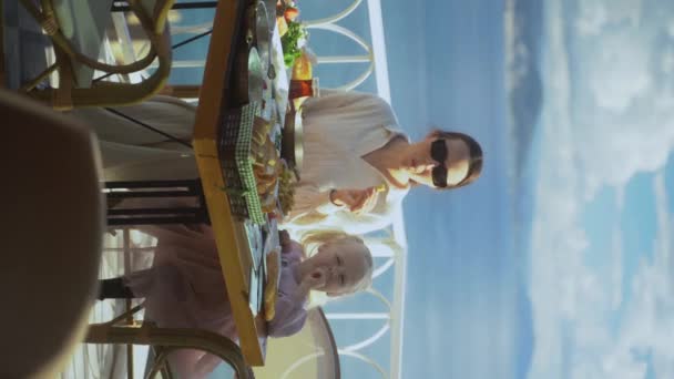 海の素晴らしい景色を望む屋外カフェで朝食を食べます かわいい女の子と彼女の母親は高級ホテル4Kのテラスで軽食を食べる — ストック動画