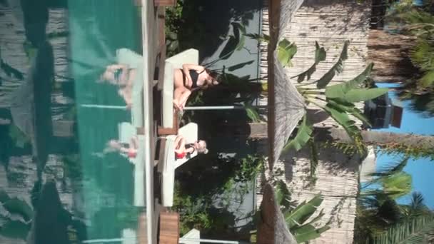 垂直视频故事卷轴 一位年轻的母亲和她年幼的女儿一起晒日光浴 在游泳池边消磨时间 单身母亲 家庭观念4K Alanya 土耳其2021 — 图库视频影像