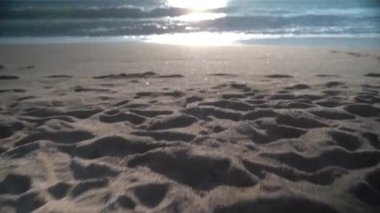 Alt açı. Kamera gün batımı denizine yaklaşırken kumdan aşağı kayıyor. Stedicam. Yüksek kalite 4k görüntü