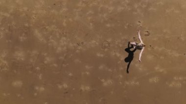 Havadan. Little Girl 'ün sahilde denizin önünde takla attığı yavaş çekim. Yüksek kalite 4k görüntü