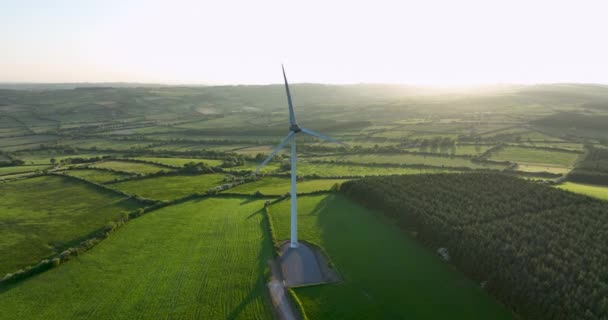 エアリアル サンセットとグリーンフィールドの背景にブレードを持つ大型風力タービン アイルランドの緑の谷の日没代替エネルギーの空中ビュー アイルランド 高品質の映像 — ストック動画