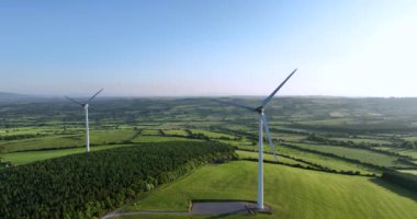 Yeşil tarlalara karşı bıçakları olan büyük bir rüzgar türbini. Ireland 'ın yeşil vadisinin havadan görünüşü. Alternatif enerji. İrlanda. Yüksek kalite 5 bin.