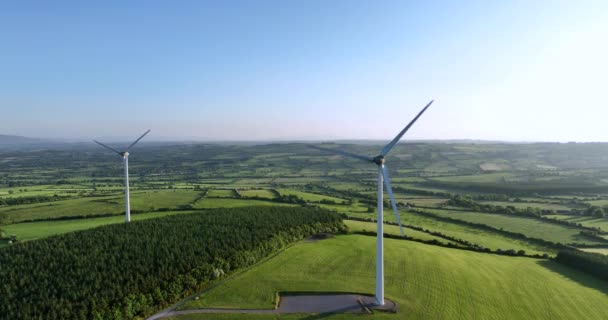 グリーンフィールドに対するブレードを持つ大型風力タービン アイランズグリーンバレーサンセット代替エネルギーの空中ビュー アイルランド 高品質 — ストック動画