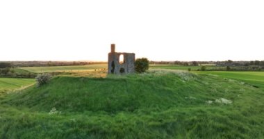 Hava. Dairesel. Eski bir tapınağın kalıntıları, Kilkenny yakınlarındaki İrlanda 'nın yeşil tarlalarına karşı bir dağın tepesinde duruyor. Gün batımı. 5 bin.