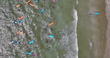 Dikey. Sahilde bir sörf okulunun kumsala yakın dalgalarda pratik yaptığı en iyi manzara. Su sporları konsepti. Slow Motion 4k görüntüleri