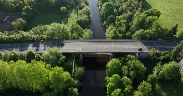 道路やキルケニー川の上の歩道橋の空中ビュー 車は橋の上を運転 アイルランド緑の木々が川を取り囲む 5K高画質映像5K — ストック動画