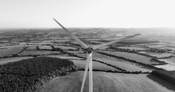 黒と白 空中だ 夕日と緑のフィールドの背景にブレードを持つ大規模な風力発電所アイルランドの緑の谷の夕日代替エネルギーの航空ビュー アイルランド 高品質の映像5K — ストック動画