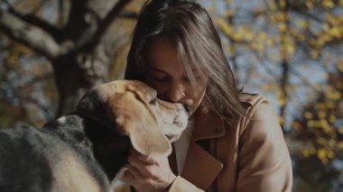 Güzel bir kız köpeğini nazikçe burnundan öper ve köpeğin başını kaşır. Gerçek aşk konsepti: köpek insanın en iyi dostudur, av köpeğini sever. Kiev 2019 Yavaş Hareket
