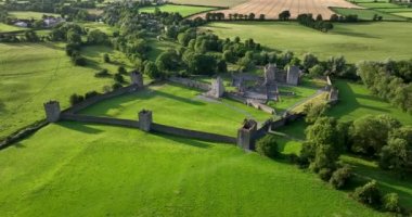 Dairesel Havacılık. İrlanda 'da yeşil bir vadi ve nehir zeminine karşı antik bir şato. Kilkenny 4k yakınlarındaki bu tarihi şehrin yeşil ağaçları Kells Manastırı