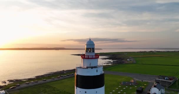 空中5K 大西洋を背景にした信じられないほどの夕日 アイルランドのウェックスフォード郡のフック半島の先端にフックヘッドに位置フック灯台 — ストック動画