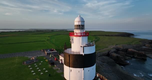 空中だ 閉めろ フック灯台は アイルランドのウェックスフォード郡のフック半島の先端にフックヘッドに位置しています アイルランドの古代灯台の周りの円形のパノラマ — ストック動画