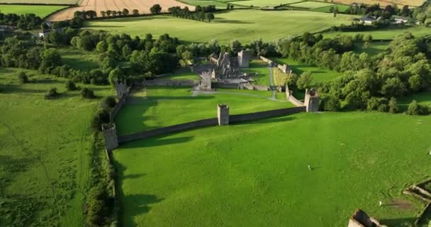 古代の城は アイルランドの緑の谷と川の背景に設定されています 美しい自然のまわりに 緑の木ケルズプリオリーはキルケニー4K近くのこの歴史的なランドマークの写真をセットアップしました — ストック動画