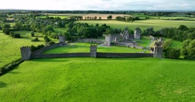 İrlanda 'da yeşil bir vadi ve nehir zeminine kurulmuş antik bir şato. Yeşil ağaçlar, Kells Manastırı. Kilkenny 4k yakınlarındaki bu tarihi yerin fotoğrafını çekiyorlar.
