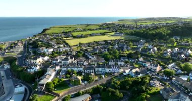 Havadan. Güzel beyaz rıhtım evleri olan sinematik kıyı şeridi. Gün batımı. Dunmore East County Waterford, İrlanda 'da. Yüksek kalite 4k görüntü