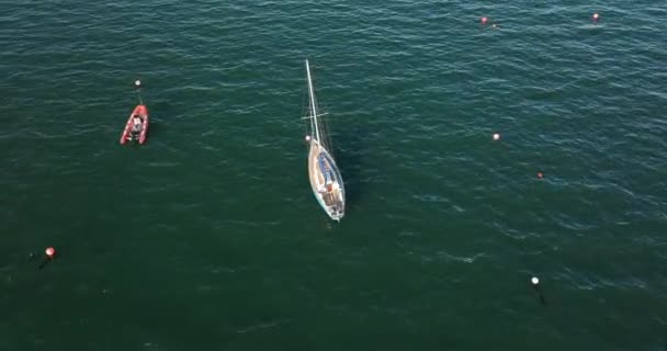 エアリアル 円形に 青い水の上にふわふわの帆が付いている白いヨットの眺め 4Kフォーマットの高品質の映像 — ストック動画
