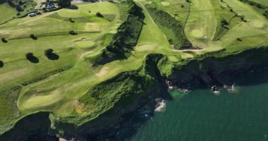 Havadan. Dairesel. Okyanusun yakınındaki kayalık kayalıklarda bir golf sahası. Dunmore East County Waterford, İrlanda 'da. Yüksek kalite 4k görüntü