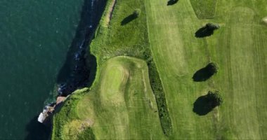 Havadan. Üzerimden uçuyor. Okyanusun yakınındaki kayalık kayalıklarda bir golf sahası. Dunmore East County Waterford, İrlanda 'da. Yüksek kalite 4k görüntü