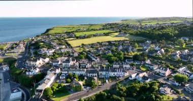 Havadan. Güzel beyaz rıhtım evleri olan sinematik kıyı şeridi. Gün batımı. Dunmore East County Waterford, İrlanda 'da. Yüksek kalite 4k görüntü