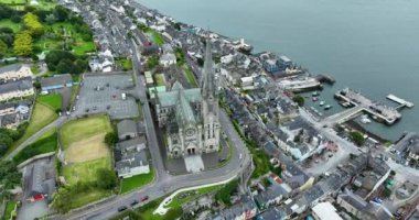 Havadan. Dairesel manzara. St Colmans Katedrali 'nin üzerinden uç. Cobh Town Şirketi, Mantar Irland. Dağda renkli evler var. Bulutlu. Yüksek kalite 4k görüntü