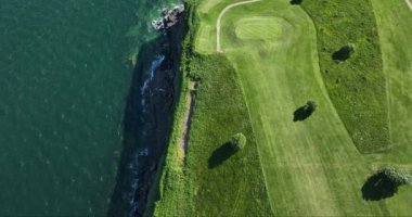 Havadan. Üzerimden uçuyor. Okyanusun yakınındaki kayalık kayalıklarda bir golf sahası. Dunmore East County Waterford, İrlanda 'da. Yüksek kalite 4k görüntü