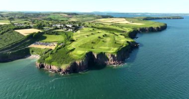 Havadan. Dairesel. Okyanusun yakınındaki kayalık kayalıklarda bir golf sahası. Dunmore East County Waterford, İrlanda 'da. Yüksek kalite 4k görüntü