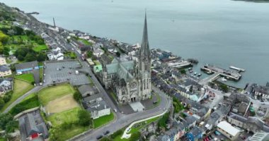 Havadan. Dairesel manzara. St Colmans Katedrali 'nin üzerinden uç. Cobh Town Şirketi, Mantar Irland. Dağda renkli evler var. Bulutlu. Yüksek kalite 4k görüntü