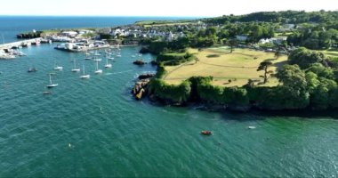 Havadan. Kayalık kıyı şeridinde balıkçı tekneleri olan çok güzel deniz feneri olan inanılmaz bir sahil şeridi. Gün batımı. Dunmore East County Waterford, İrlanda 'da. Yüksek kalite 4k görüntü