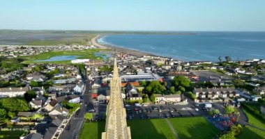 Havadan. Tüm kıyı kasabası Tramore, İrlanda 'ya bakan Kutsal Haç Katolik Kilisesi üzerinde uçuyor. Güneşli bir gün. Yüksek kalite 4k görüntü