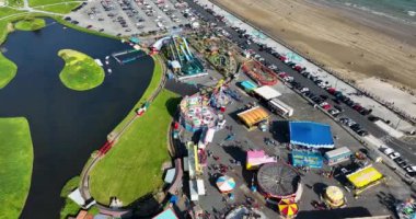 Havadan. Dairesel. Tramore İrlanda 'daki Atlantik Okyanusu sahilinin arka planına karşı bir lunapark. Aile tatili. Meslek. Deniz kenarında. Yüksek kalite 4k görüntü
