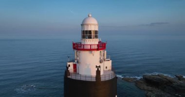Hava 4k. Yeşil tarlalar ve saman denizine karşı kocaman bir deniz feneri. Wexford, İrlanda 'daki Hook Yarımadası. Dünyanın en eski deniz feneri 12. yüzyılda inşa edildi.