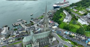 Havadan. Dairesel manzara. St Colmans Katedrali 'nin üzerinden uç. Cobh Town Şirketi, Mantar Irland. Dağda renkli evler var. Bulutlu. Yüksek kalite 4k görüntü