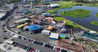 Havadan. Dairesel. Tramore 'daki Atlantik Okyanusu sahilinin arka planına karşı bir lunapark. Aile tatili. Meslek. Deniz kenarında. Yüksek kalite 4k görüntü