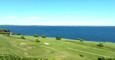 Havadan. Üzerimden uçuyor. Okyanusun yakınındaki kayalık kayalıklarda bir golf sahası. Dunmore East County Waterford, İrlanda 'da. Yüksek kalite 4k görüntü