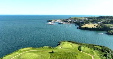 Havadan. Üzerimden uçuyor. Okyanusun yakınındaki kayalık kayalıklarda bir golf sahası. Dunmore East County Waterford, İrlanda 'da. Yüksek kalite 4k görüntü