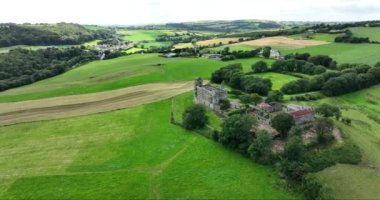 Havadan. Dairesel. İrlanda 'da pitoresk bir kırsal alana karşı antik bir kale inşa edildi. Küçük bir çiftlik. Kilbrittain Ormanı. 4k biçiminde yüksek kaliteli görüntüler