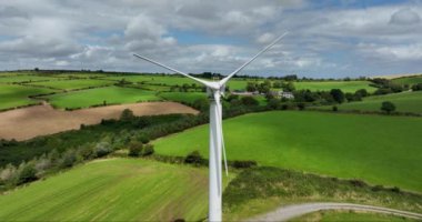 Havadan. Yel değirmeni yavaşça İrlanda 'nın yeşil alanlarına karşı döner. Alternatif enerji. İrlanda. Yüksek kalite 4k