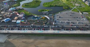 Havadan. Eğlence parkı manzarası ve sahil boyunca büyük bir otopark. Meslek. Deniz kıyısında. Yüksek kalite 4k görüntü