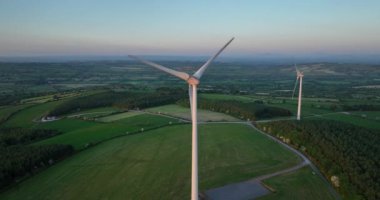 Havadan. Gün batımında duran devasa türbinler. Rüzgâr türbinli bir çiftliğin havadan çekilmiş fotoğrafı. Temiz yenilenebilir enerji üretiliyor. Alternatif enerji. Yüksek kalite 4k görüntü