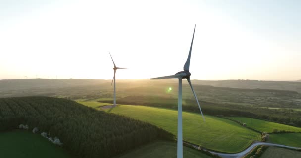 エアリアル4K 風力タービンは日没時に立っています 風力タービンが付いている農場の航空写真 クリーンな再生可能エネルギーを生み出します 外部エネルギー — ストック動画